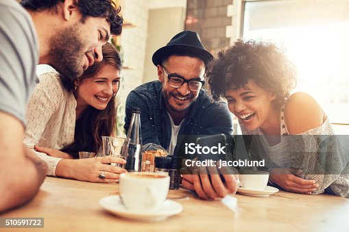 istock Friends looking at smart phone while sitting in cafe 510591722