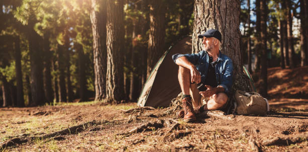 homem maduro sentado em um parque de campismo - forest sitting men comfortable imagens e fotografias de stock