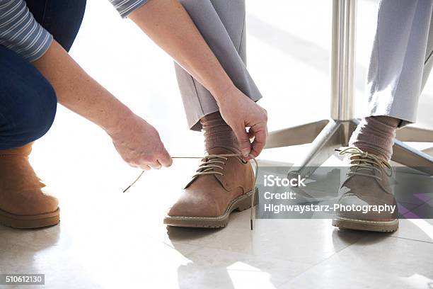 Adult Daughter Helping Senior Tie Shoelaces Stock Photo - Download Image Now - Assistance, Getting Dressed, Support