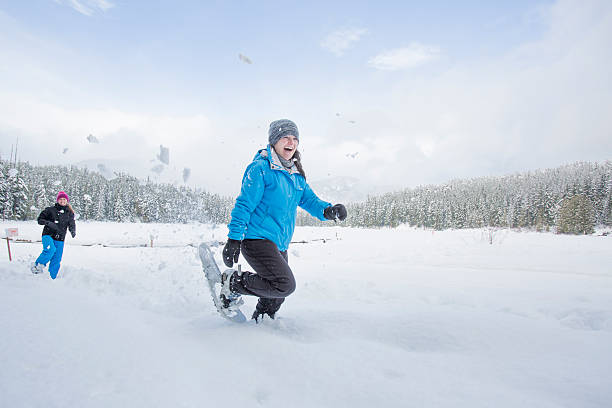 grupo de mulheres amigos de caminhadas com raquetes de neve e com guerra de bolas de neve. - snowshoeing winter sport snowshoe hiking - fotografias e filmes do acervo