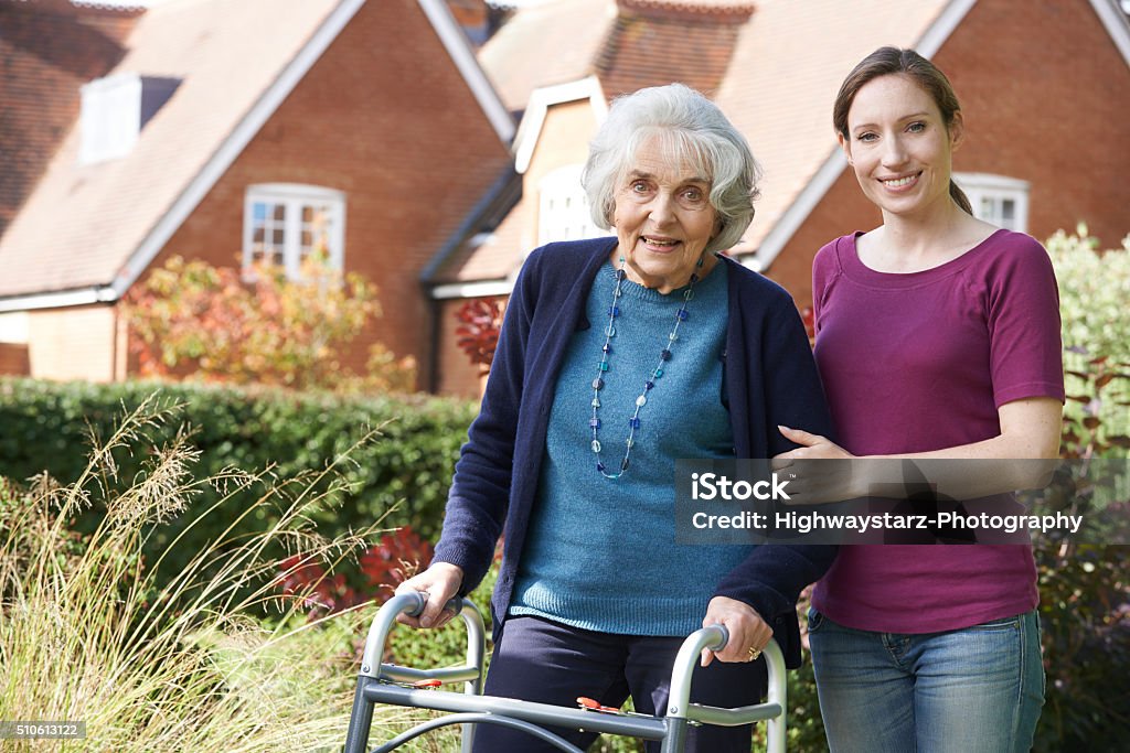 Daughter Helping Senior Mother To Use Walking Frame Community Outreach Stock Photo