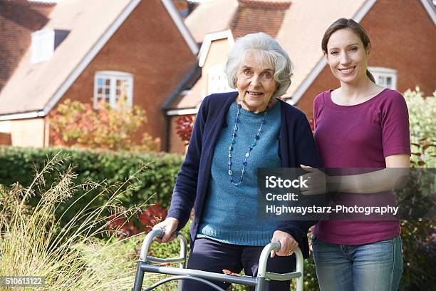 Daughter Helping Senior Mother To Use Walking Frame Stock Photo - Download Image Now