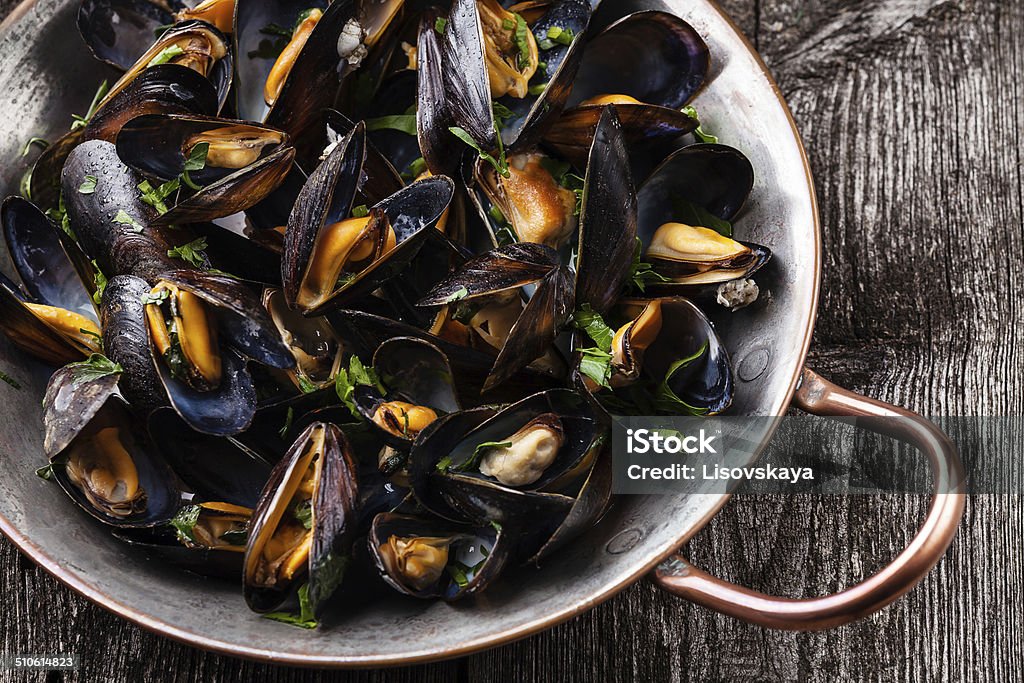 Boiled mussels Boiled mussels in copper cooking dish on dark wooden background close up Mussel Stock Photo