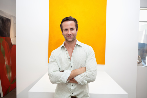 Half-length portrait of smiling young man in front of yellow painting