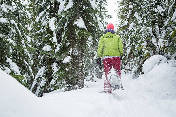 donna corre con le racchette lontano dalla fotocamera. - winter snowshoeing running snowshoe foto e immagini stock