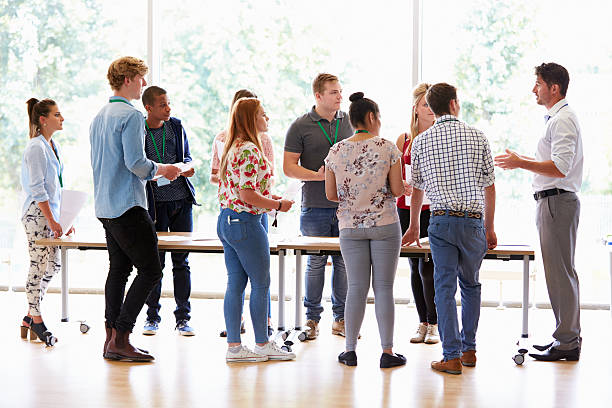 istock Teacher With College Students Standing By Desks In Classroom 510615439