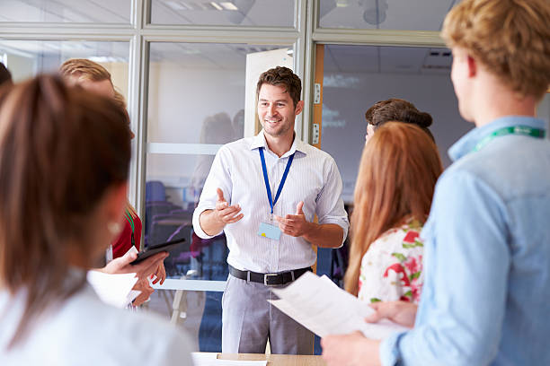 istock Teacher With College Students Standing By Desks In Classroom 510615457