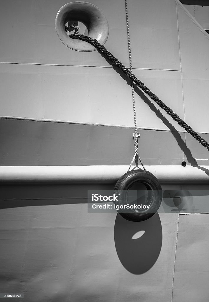 Car tire hanging off the side of the ship Car tire hanging off the side of the ship, black and white photo Bumper Stock Photo