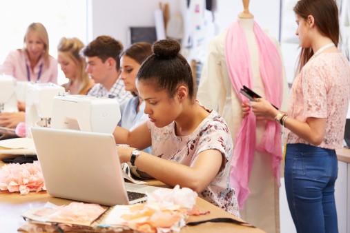 College Students Studying Fashion And Design With Sewing Machines