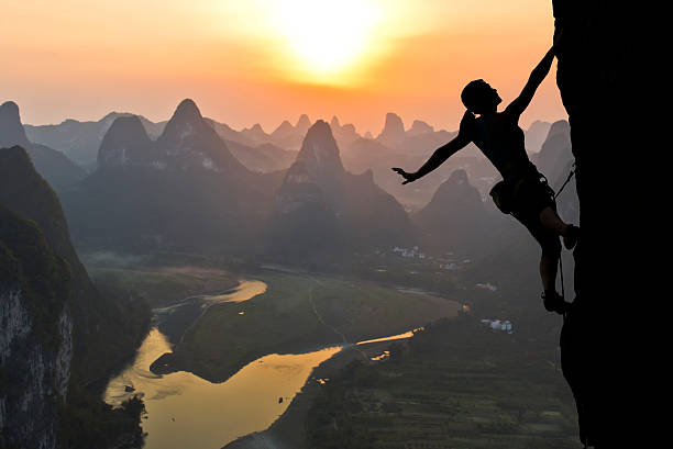 Female climber silhouette against the sunset Elegant female extreme climber silhouette against the sunset over the river. China, typical Chinese landscape with mountains and river li river stock pictures, royalty-free photos & images