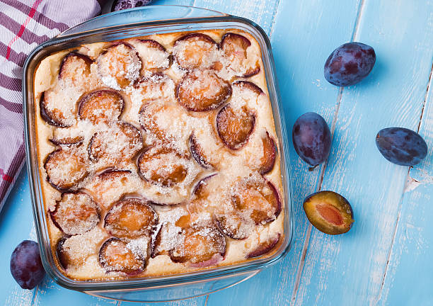 Homemade clafoutis with plums Delicious homemade clafoutis with plums on the blue colored table clafoutis stock pictures, royalty-free photos & images