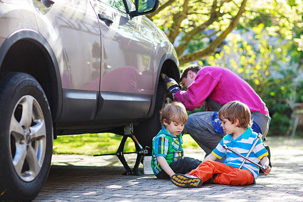 istock father, two little boys repairing car and changing wheel 510619105