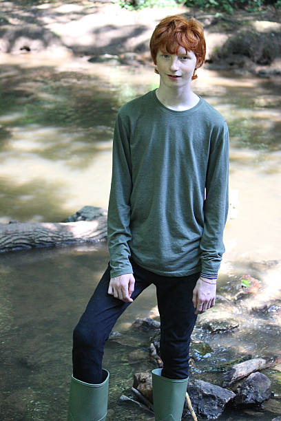 Boy Wading In Shallow River With Green 