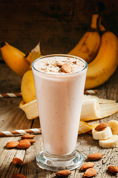 банановый смузи с молоком, пол миндаля в скорлупе - smoothie banana smoothie milk shake banana стоковые фото и изображения