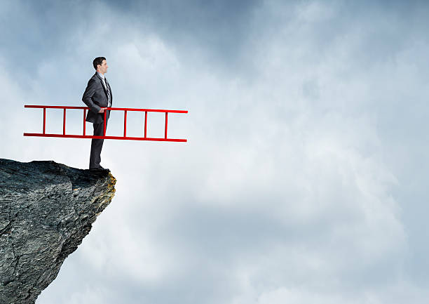 empresario con escalera de color rojo en el borde del acantilado - cliff ladder business problems fotografías e imágenes de stock