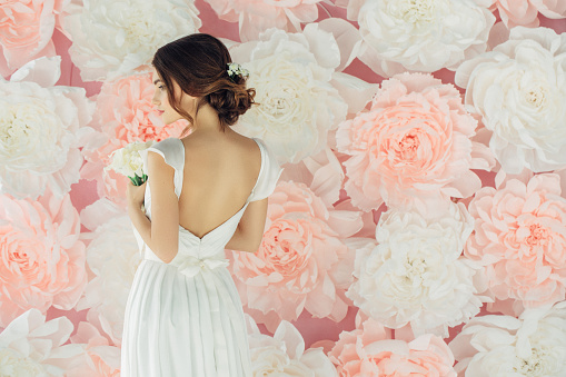 Studio shot of young beautiful bride on background of flowers. Professional make-up and hairstyle.