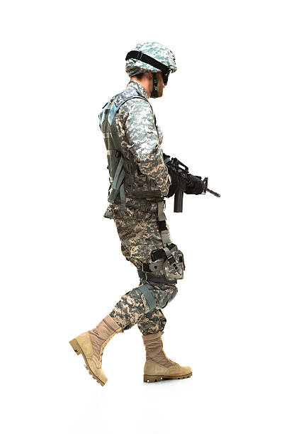 Rear view of army holding rifle and walking