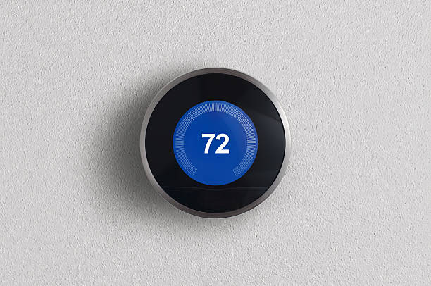 Modern Digital Thermostat A simplistic photo of a round, modern, programmable digital thermostat, on a clean white wall in cooling mode. thermostat photos stock pictures, royalty-free photos & images