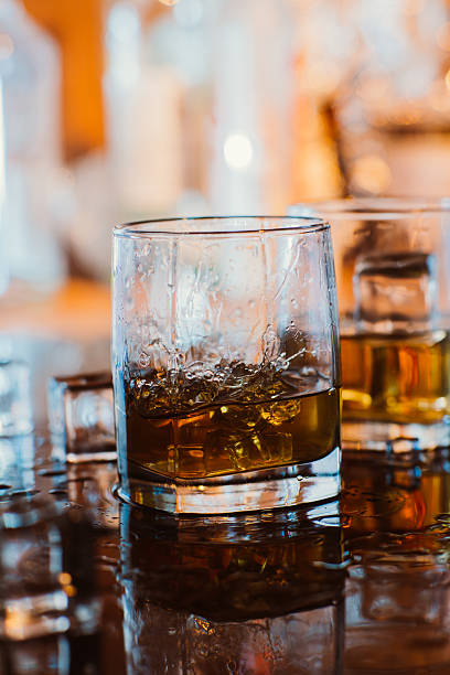 istock whiskey glass with ice and warm light on black table 510630034