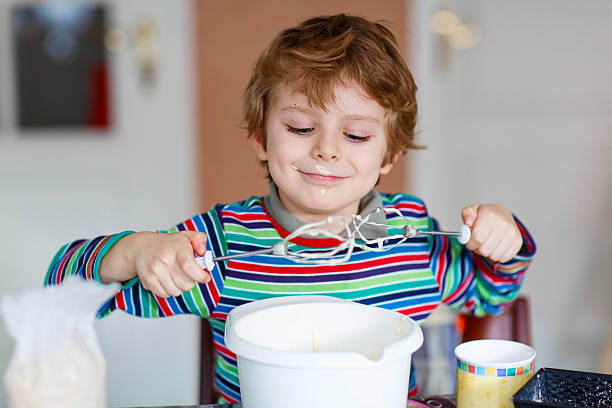 istock Funny blond kid boy baking cake indoors 510630432