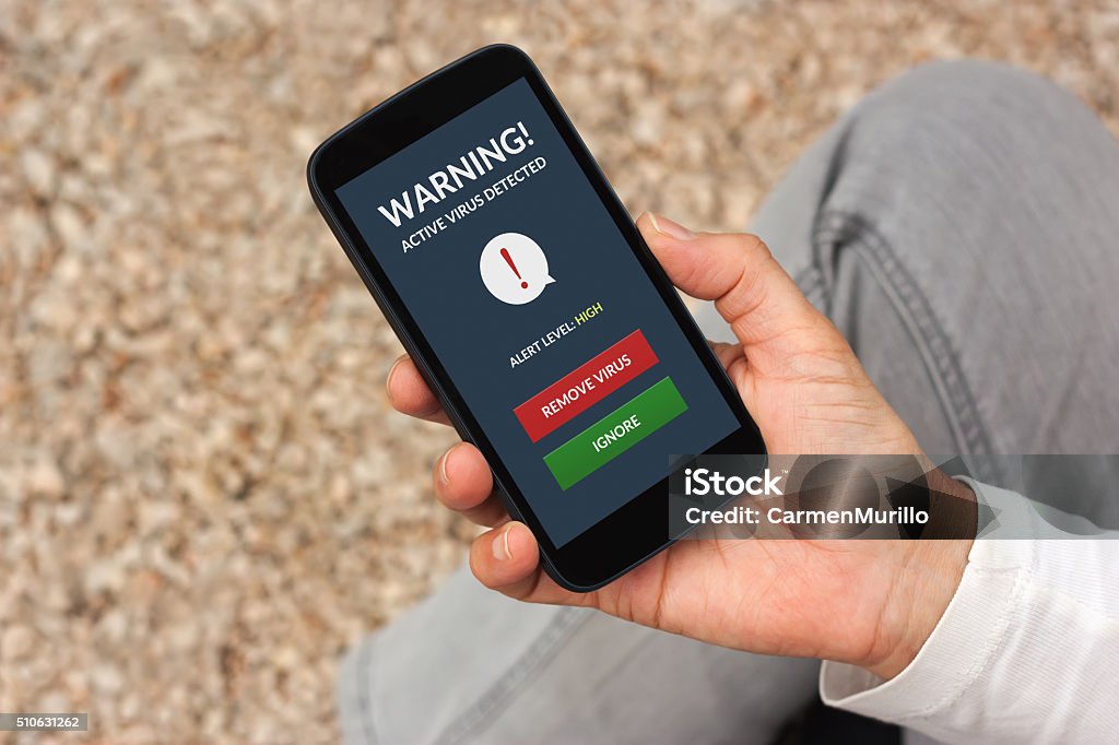Hand holding smartphone with virus alert on screen Hand holding smartphone with virus alert on screen. All screen content is designed by me Adult Stock Photo