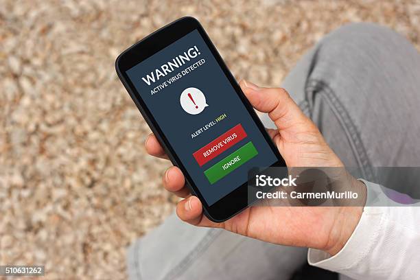 Hand Holding Smartphone With Virus Alert On Screen Stock Photo - Download Image Now - Adult, Alertness, Close-up