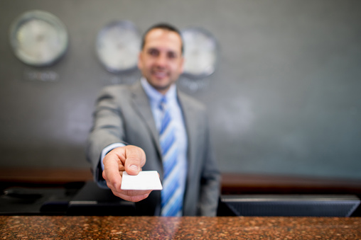 Man handling card key at the front desk of a hotel - people travel concepts