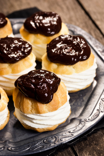 Profiteroles (or Cream Puffs or Choux à la Crème) are a French dessert made from choux pastry that is baked, cut in half and filled with pastry cream, whipped cream or soft serve ice cream and then topped with warm chocolate sauce.