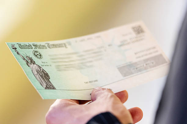 Tax refund Men hands holding a US Government Treasury check attraction studio photography stock pictures, royalty-free photos & images