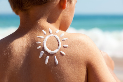 Child with suntan lotion shaped as a sun on his back at the beach concept for sun protection and skin care for children