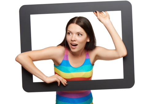 Surprised young woman scrambling out of tablet frame, over white background