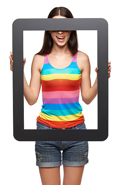 Woman looking through tablet frame Bright playful young woman standing holding tablet frame, hiding eyes, over white background person holding frame over face stock pictures, royalty-free photos & images