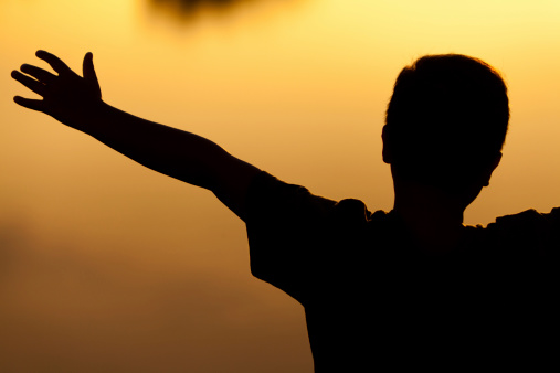 Young man with outstretched arms, sunset lake scenery