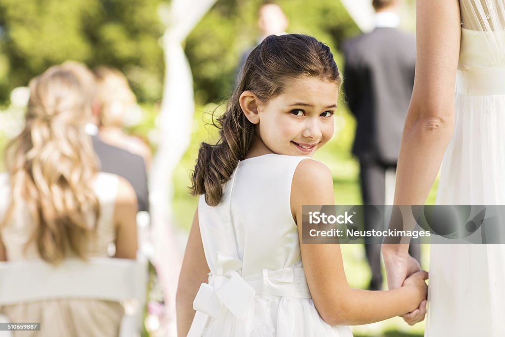 Flower Girl Holding Bride's Hand During Outdoor Wedding Portrait of flower girl looking over shoulder holding bride's hand during outdoor wedding. Horizontal shot. 20-29 Years Stock Photo