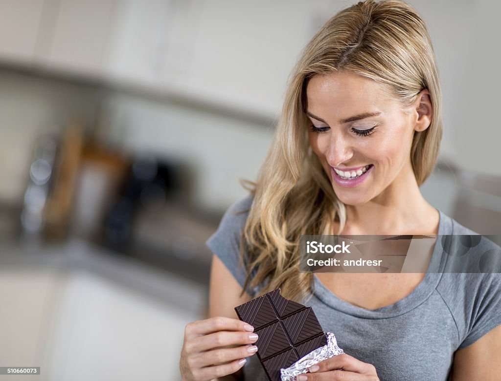 Woman eating a chocolate candy Happy woman eating a chocolate candy Eating Stock Photo