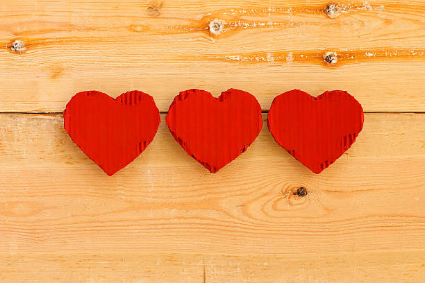 istock Love Valentines red cardboard hearts on rough pine background 510660655