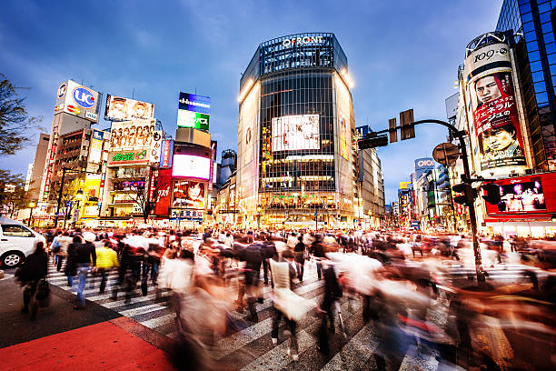 Shibuya Crossing In Tokyo, Japan The world famous crossroad in Shibuya, Tokyo with commuters at dusk. Need more Tokyo images: shibuya district stock pictures, royalty-free photos & images