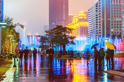 Modern skyscrapers in Canton(Guangzhou),fountain, south east China,night,people abstract,umbrellas, evening, decoration in front.Nikon D3x