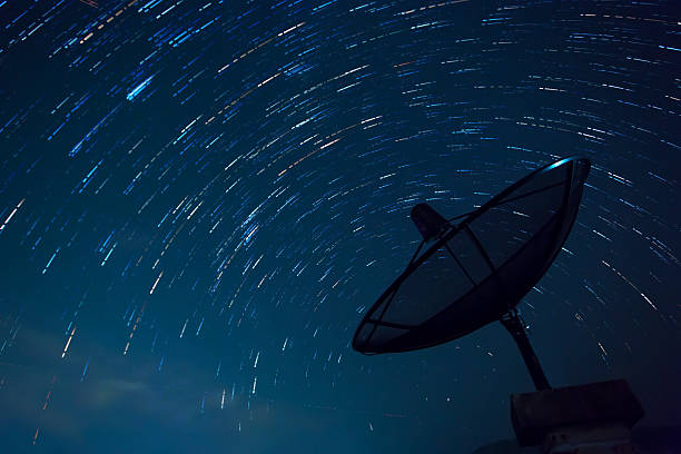 piatto con canali satellitari e stelle sentieri. cielo blu. - parabolic mirror foto e immagini stock