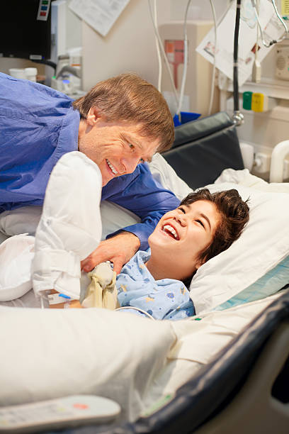 istock Father watching over disabled son in hospital bed 510694802