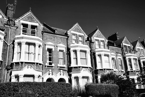 Black and white image of old fashioned typical Victorian terraced town houses architecture in London, England, UK. These residential homes are often turned into apartment flats