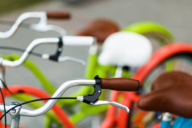 Closeup of the three woman's bright colored bicycle's handlebars with hand break hook and leather saddles