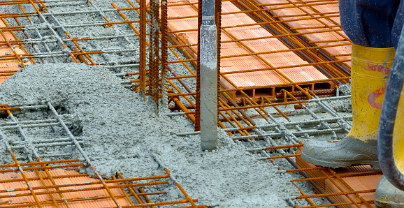 Construction worker compacting liquid cement in reinforcement form work during concreting floors pouring works