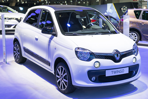 Brussels, Belgium - Januari 12, 2016: White Renault Twingo compact car front view The car is on display during the 2016 Brussels Motor Show. The car is displayed on a motor show stand, with lights reflecting off of the body. There are people looking around and other cars on display in the background.
