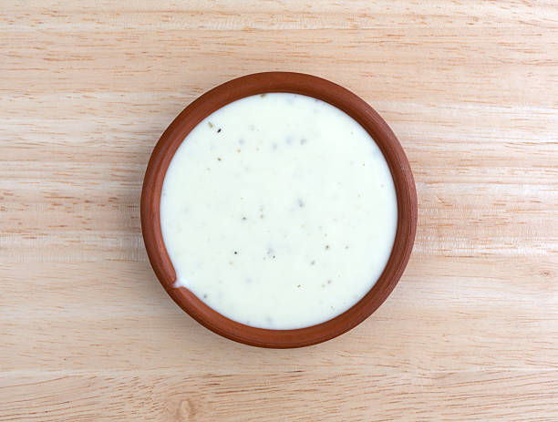 Bowl of ranch dressing on a wood table top view Top view of a small bowl of ranch dressing on a wood table top illuminated with natural light. ranch dressing stock pictures, royalty-free photos & images