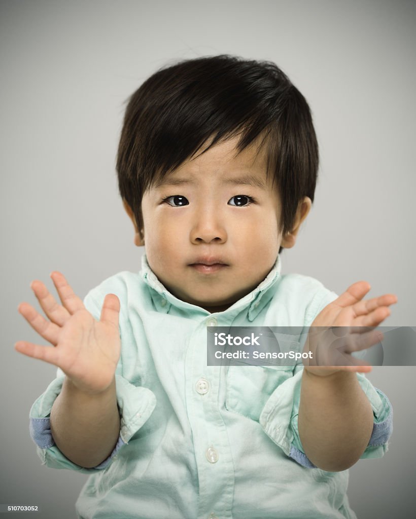 Portrait of a japanese baby. Studio portrait of a real japanese 1'5 years old baby looking at camera and doubting. Vertical color image from a medium format digital camera. Sharp focus on eyes. Japanese Ethnicity Stock Photo