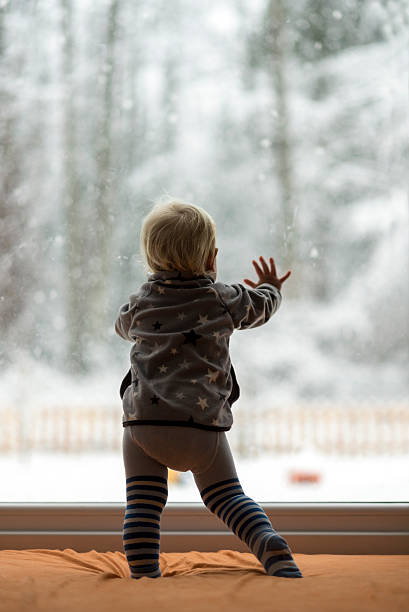 istock Toddler boy standing up against a window looking out 510703466
