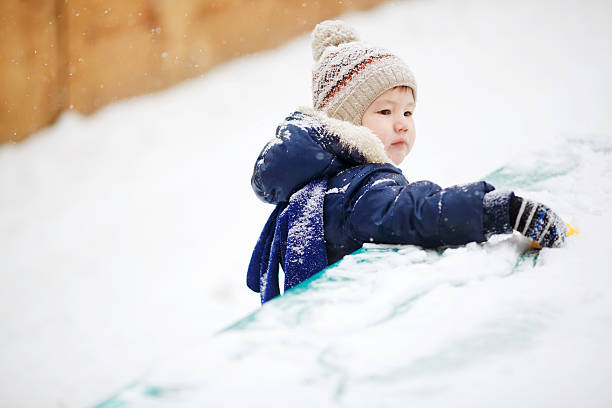 Little boy playing alone with toy in snow, close up stock photo