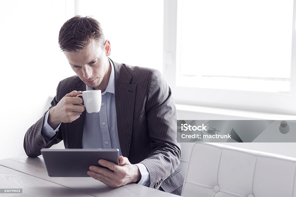 Businessman reading Businessman reading on a tablet pc at the office Adult Stock Photo
