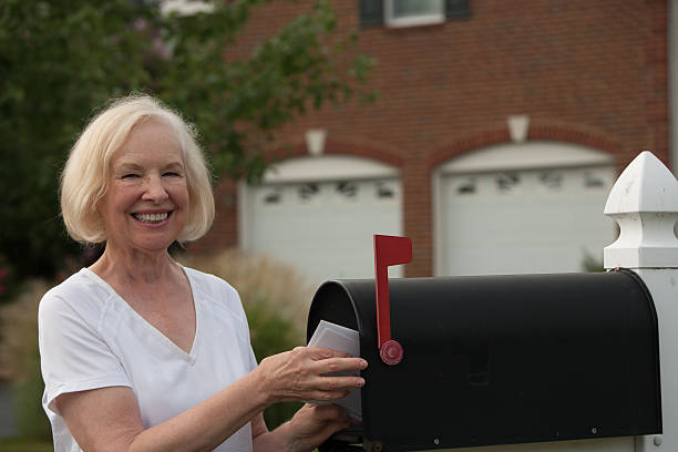 istock Smiling senior woman putting mail from her mailbox 510723189